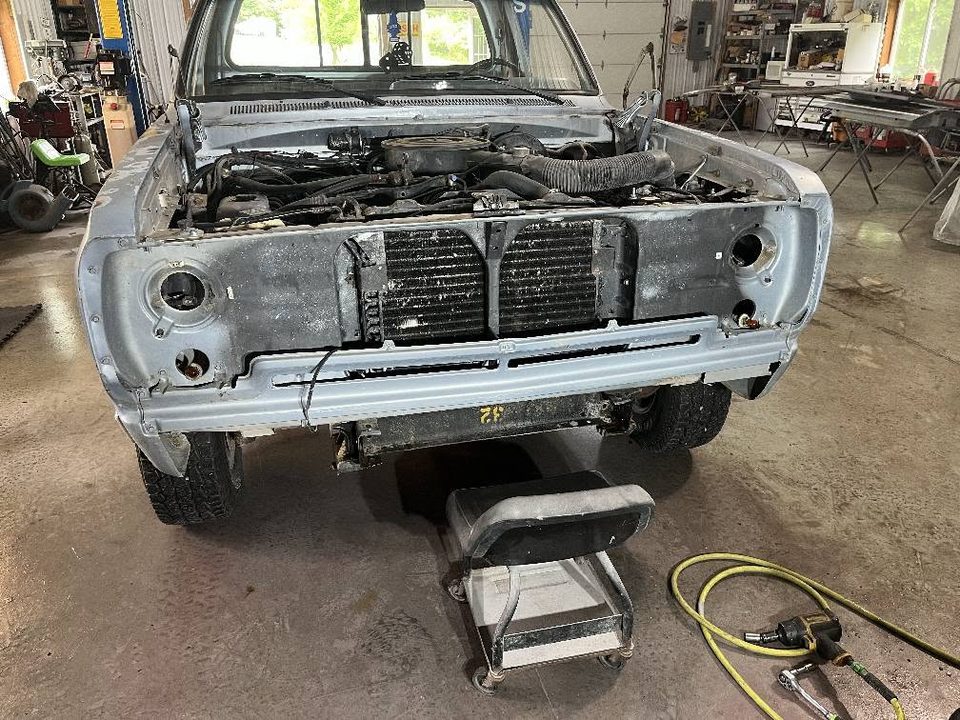 A classic Dodge pickup stripped to bare metal at the front end during restoration