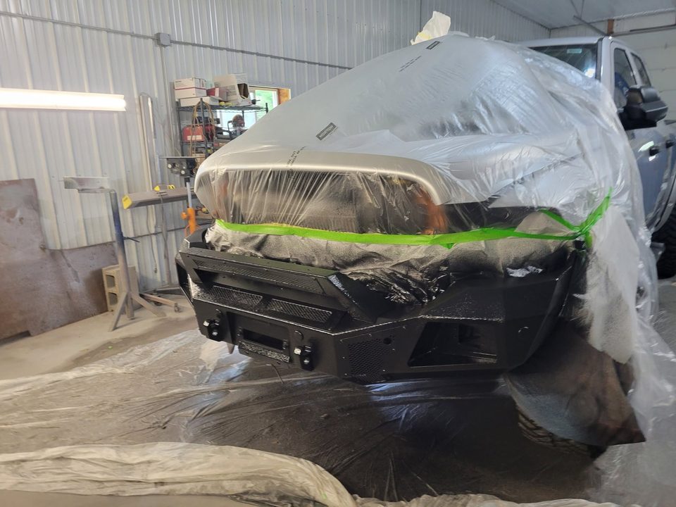 A front bumper assembly masked and freshly finished in the paint booth