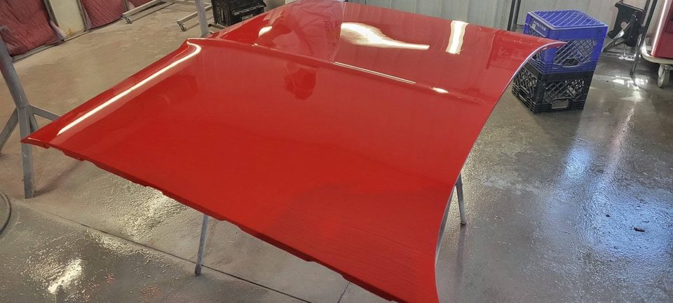 Close-up of a mirror-gloss red finish reflecting the shop lights