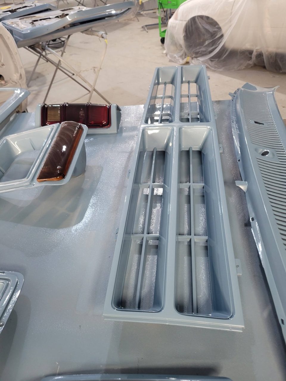Freshly refinished trim and lamp assemblies laid out on the finishing stands