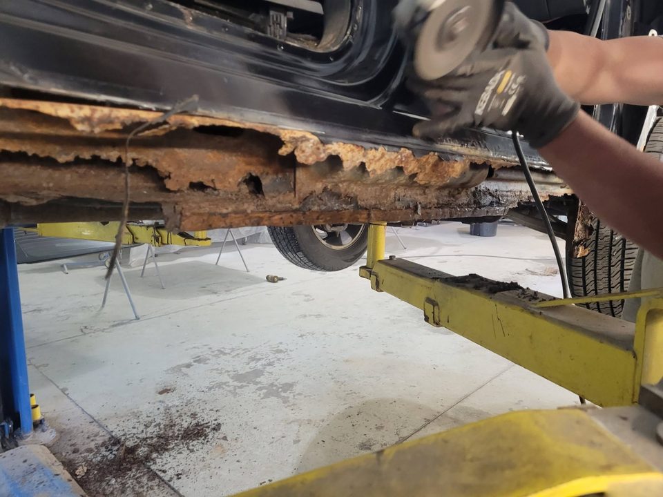 Cutting out a rusted-through rocker on a vehicle raised on the lift