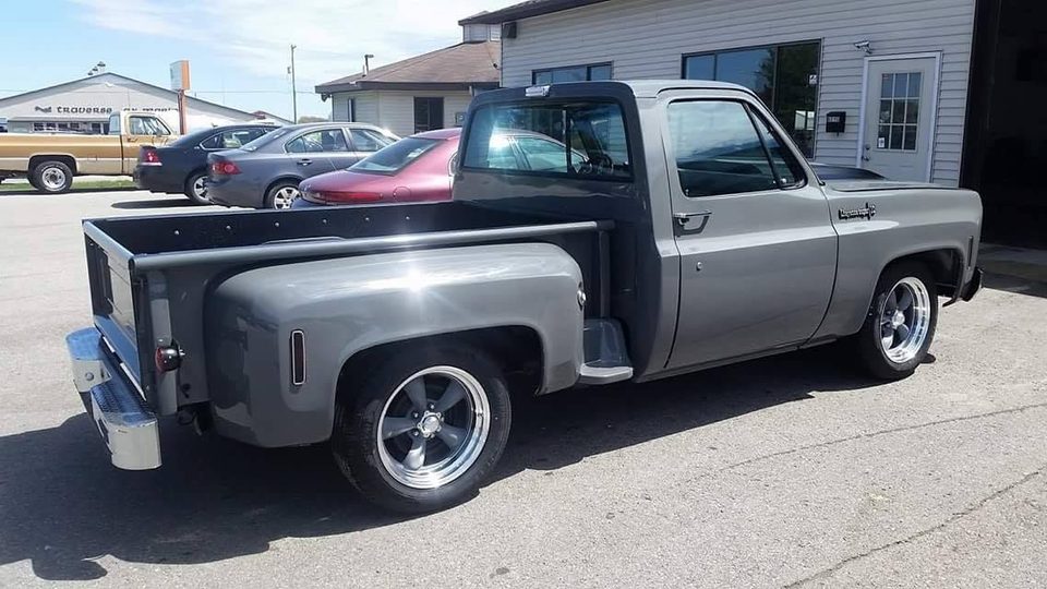 A silver square-body Chevrolet stepside outside the shop